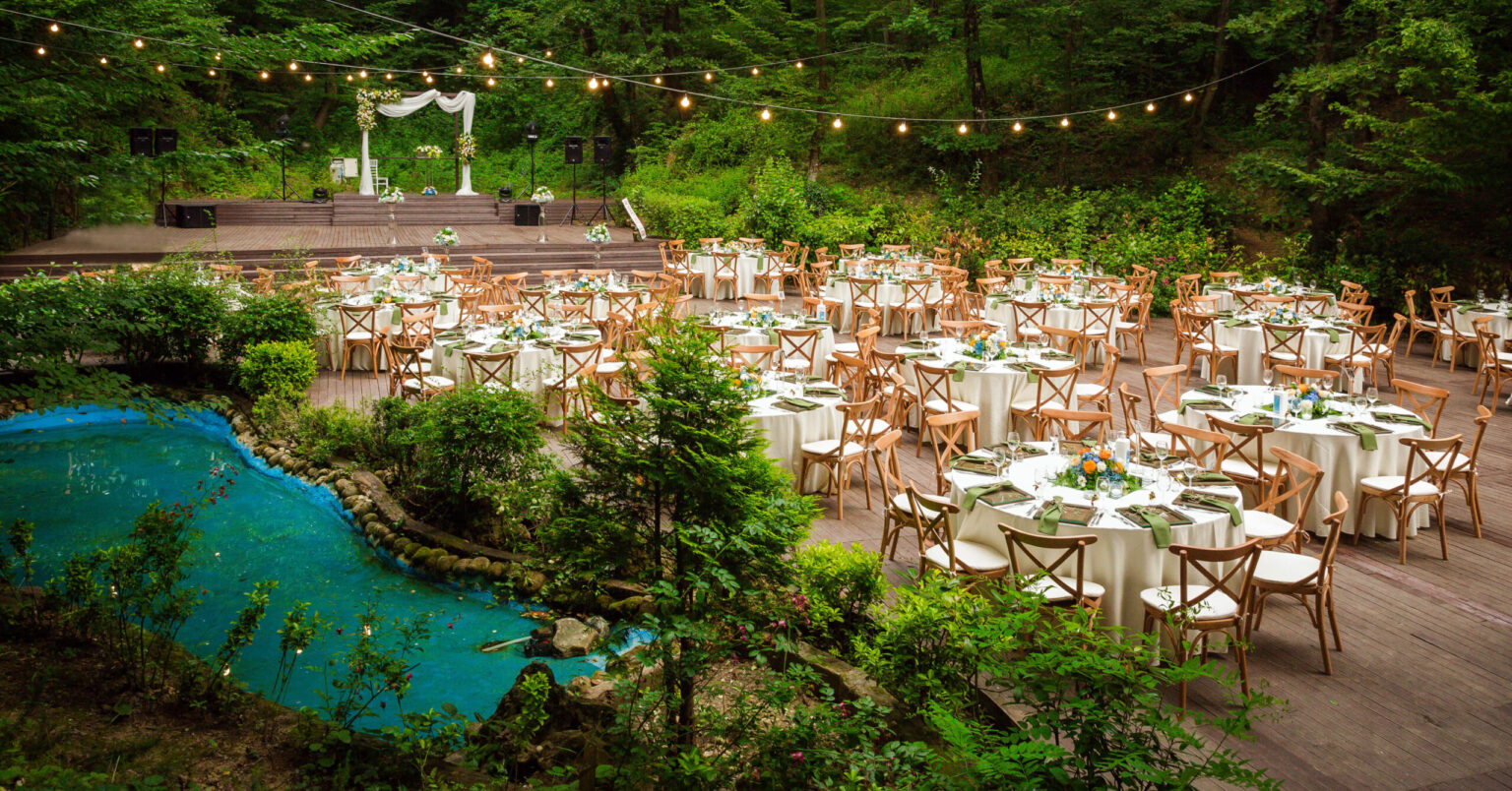 Kır düğünü konsepti için çiçeklerle süslenmiş, ahşap zeminli davet alanı.